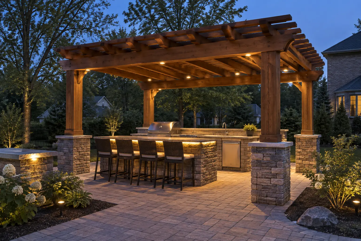 Wood pergola with beam downlights over an outdoor kitchen counter and bar stools
