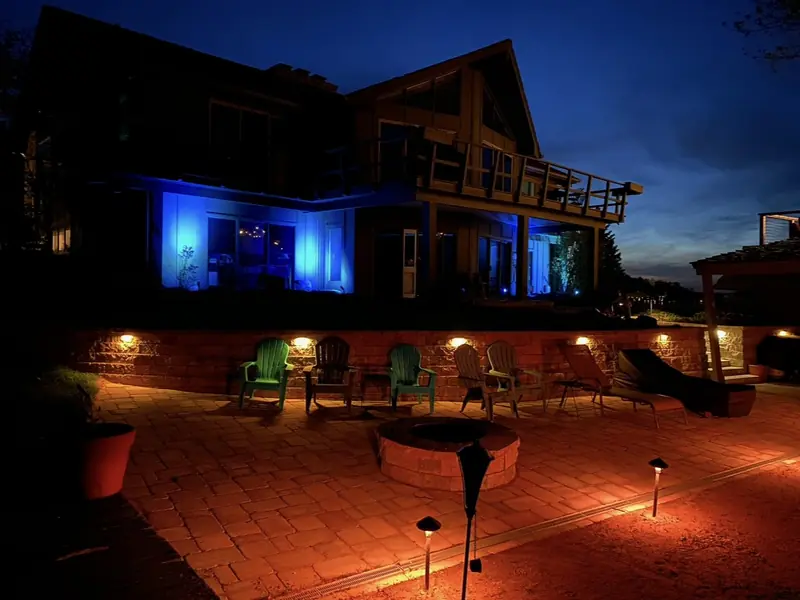 Paver patio with a round fire pit and path lights at night