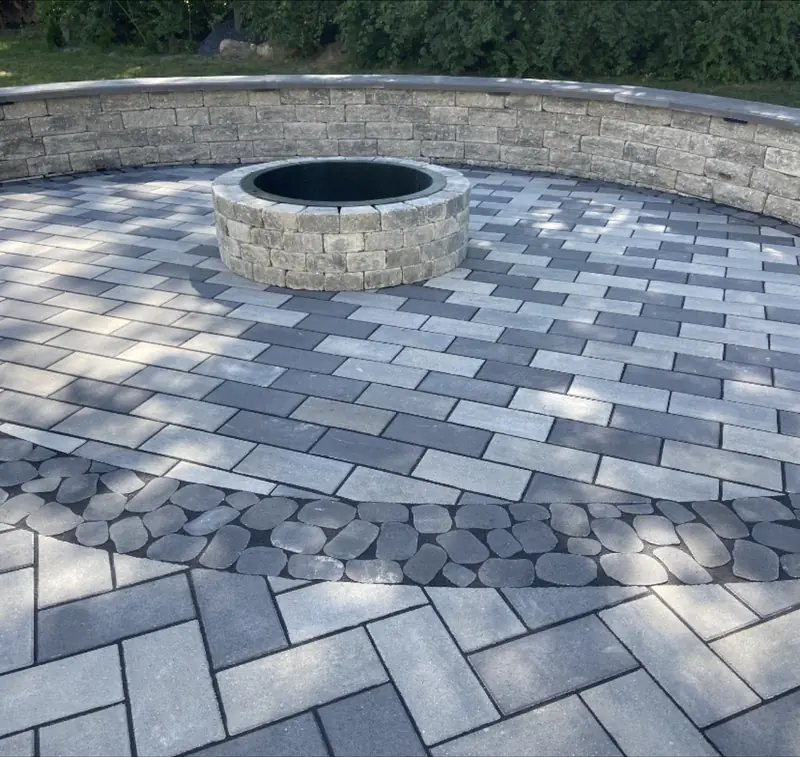 Round stone fire pit on a paver patio with a curved seat wall