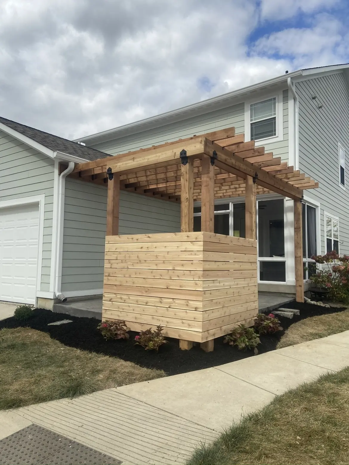 Cedar privacy screen with a pergola top beside fresh mulch beds in Indianapolis