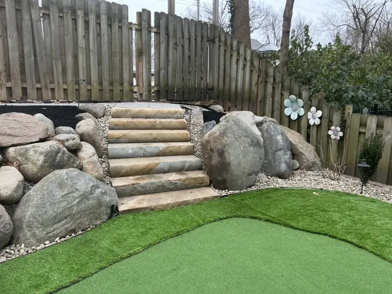 Artificial putting green below natural stone steps and boulders
