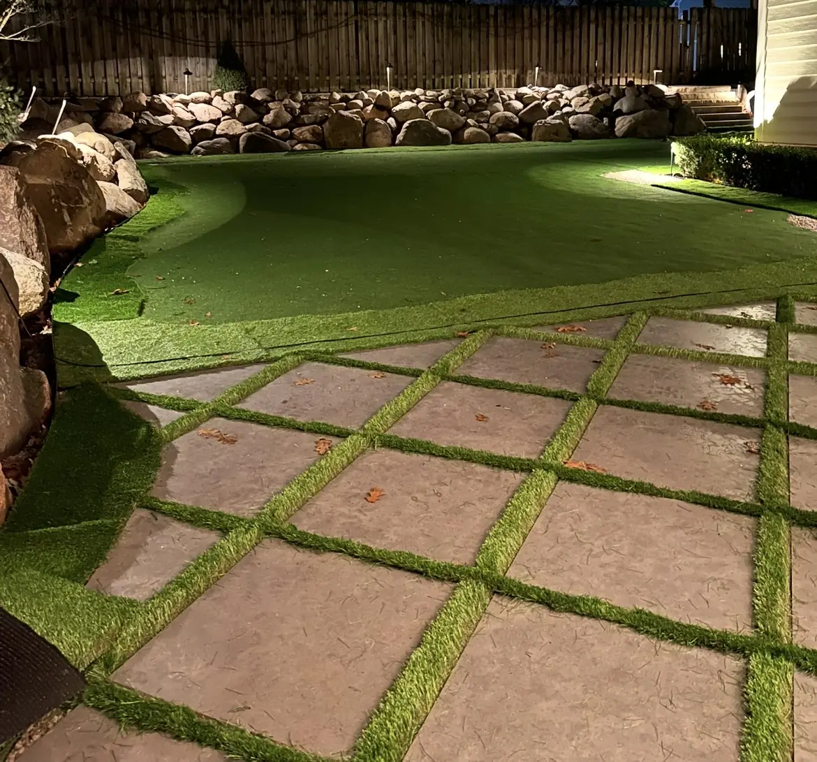 Artificial putting green and paver steppers lit at night in Indianapolis