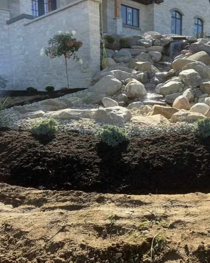 Boulder waterfall and stream running down a landscaped slope