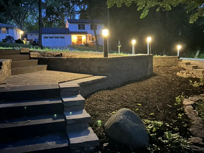 Bollard path lights along a block retaining wall and steps at dusk in Carmel, IN
