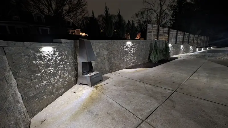 Retaining wall lit by wall lights beside a patio at night