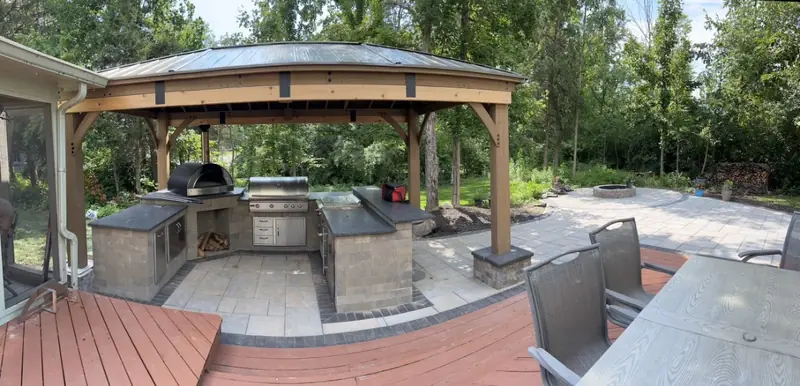 Outdoor kitchen with a pizza oven and grill under a cedar pavilion