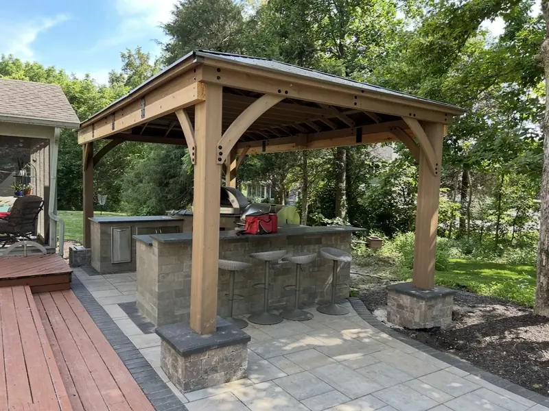 Outdoor kitchen bar with stools under a cedar pavilion