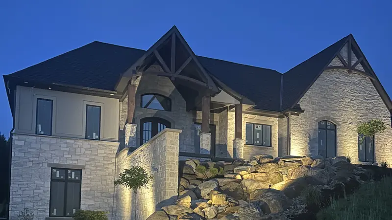 Warm uplighting on a stone home and boulder slope at dusk in Indianapolis