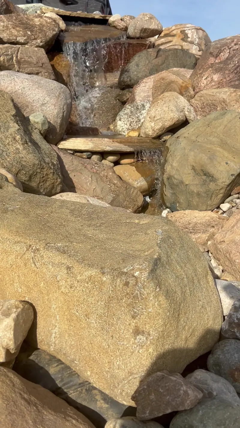 Water spilling over boulders at the top of a pondless waterfall in Indianapolis