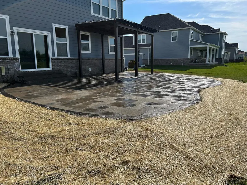Dark-stained pergola over a curved paver patio in Carmel, IN