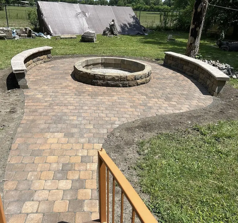 Paver patio with a round fire pit between two curved seat walls in Indianapolis